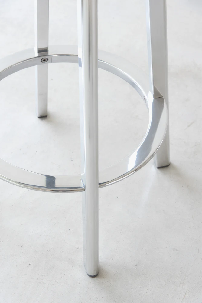 Close-up of metal stool base and ring footrest showing curved chrome ring