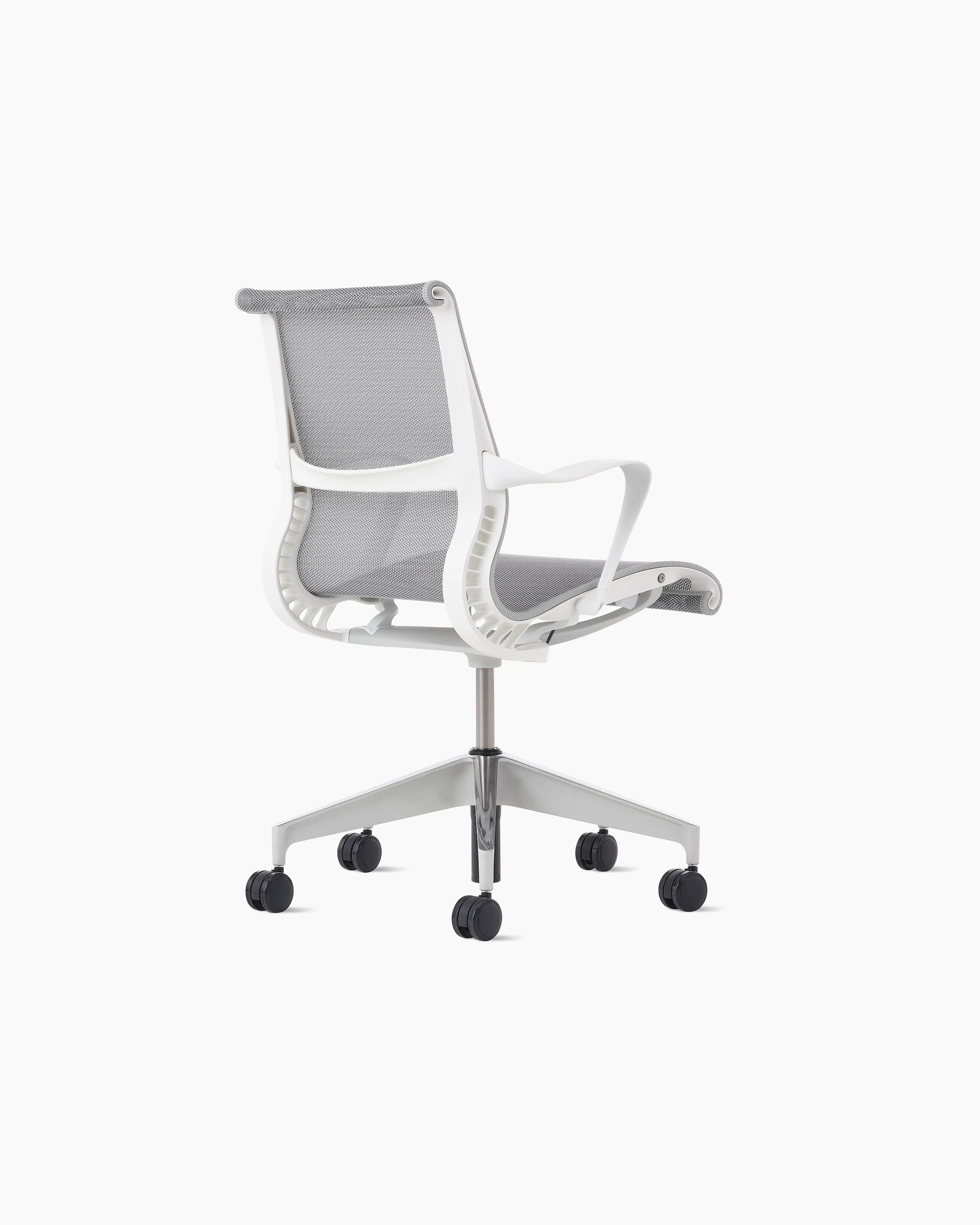 Rear angle view of a Setu chair with a white frame, grey suspension and semi polished base.