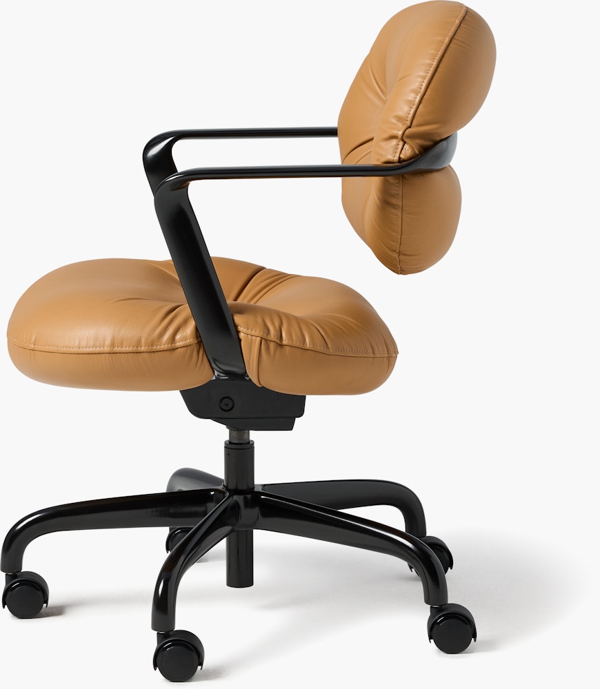Side view of a Morrison Hannah chair with a black frame and base with fixed arms and light brown leather upholstery.