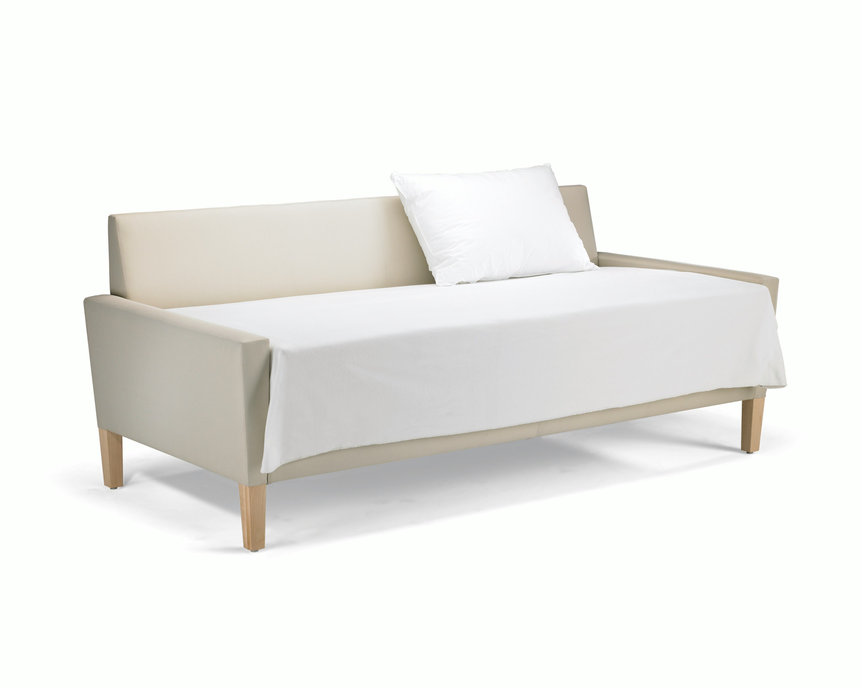 A Brava Flop Sofa in white textile with maple legs converted to sleep surface with sheets and pillow.