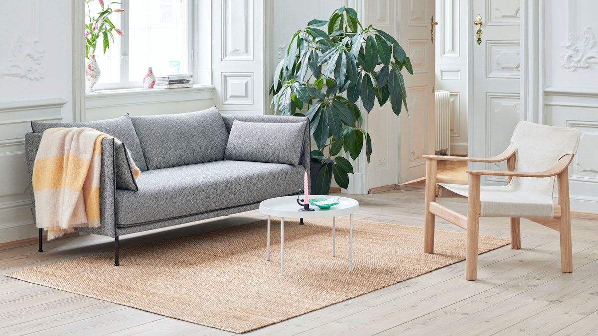 A tan Bernard Lounge Chair next to a grey Silhouette Sofa and a white Tulou Coffee Table.