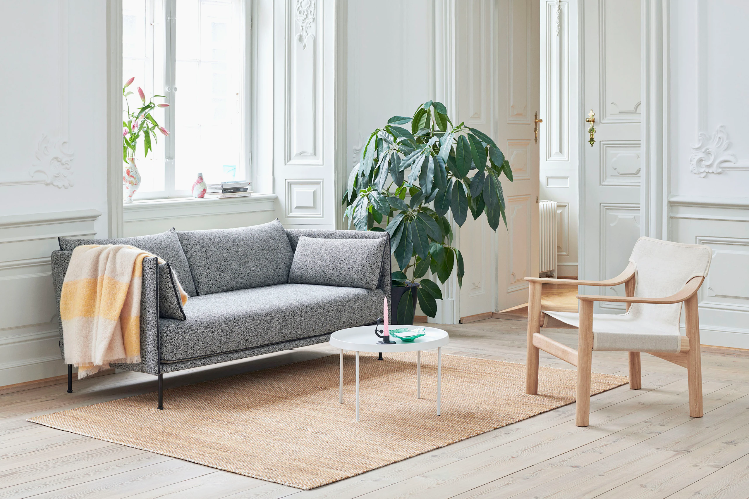 A tan Bernard Lounge Chair next to a grey Silhouette Sofa and a white Tulou Coffee Table.