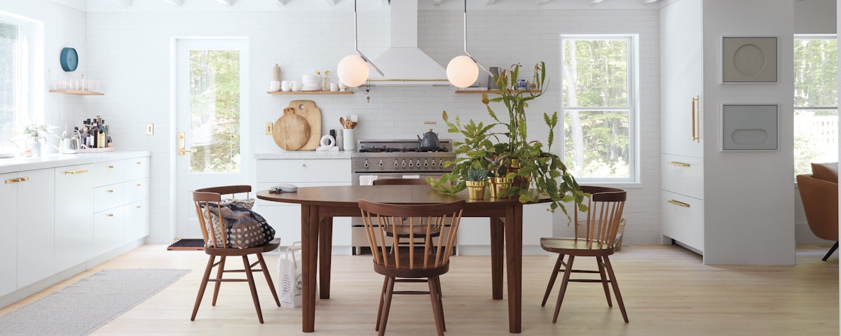 IC Pendants above a Gala Extension Dining Table and Nakashima Straight-Back Chairs in a kitchen dining setting