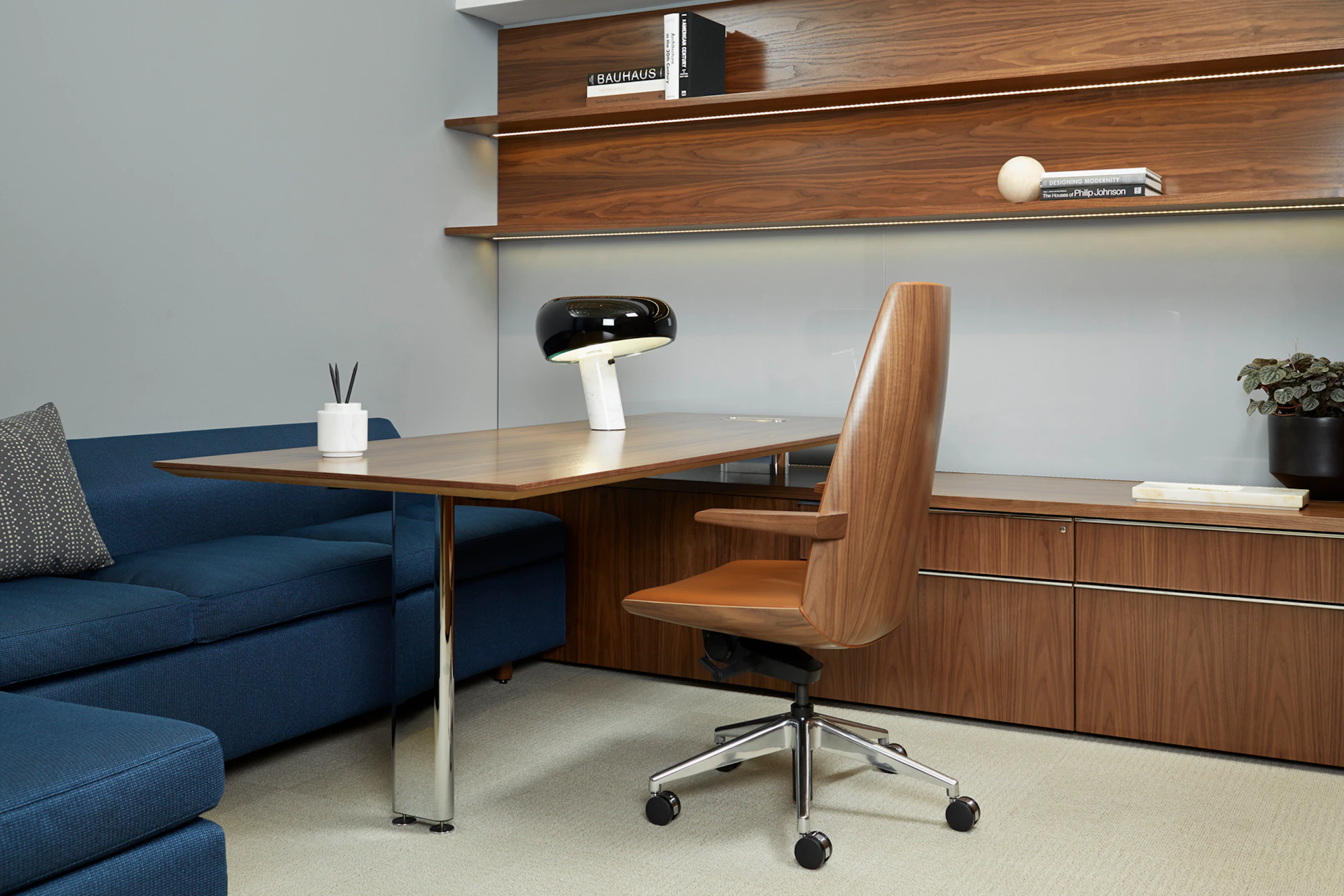 A Geiger Levels Casegoods private office with two tiers of work surface and a Clamshell Chair with a veneer shell and orange upholstery.