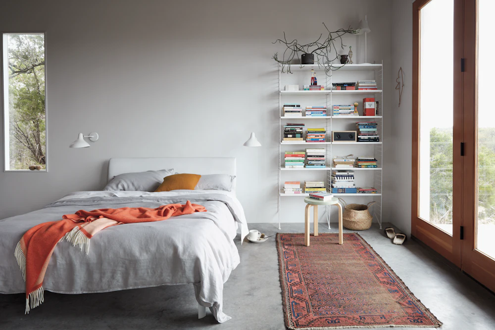 Bedroom with white shelving unit filled with books and decor