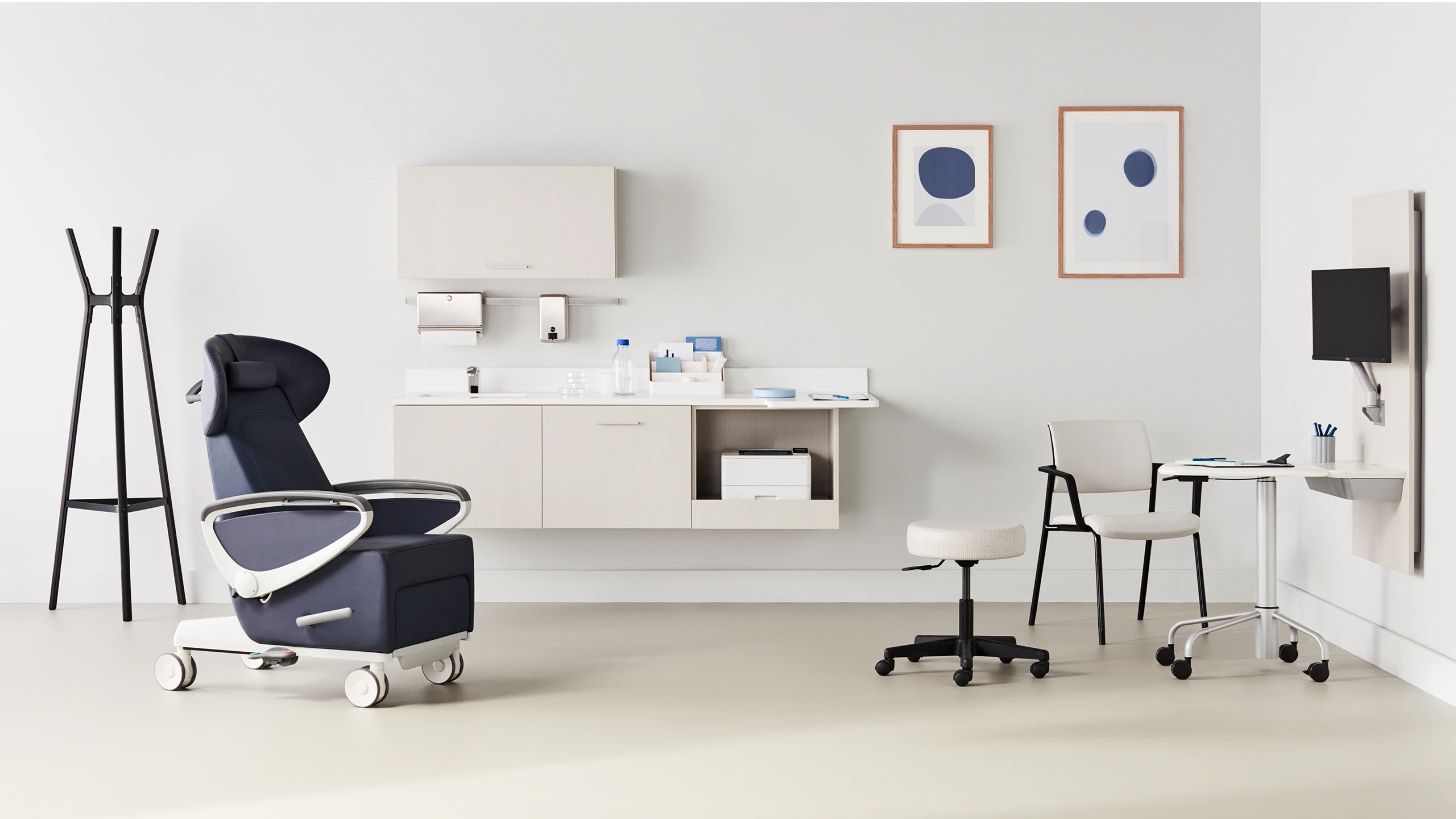 Exam room with a dark blue Ava recliner and an Intent Solution mobile, height-adjustable table and wall unit to the side with a physician stool and Verus side chair