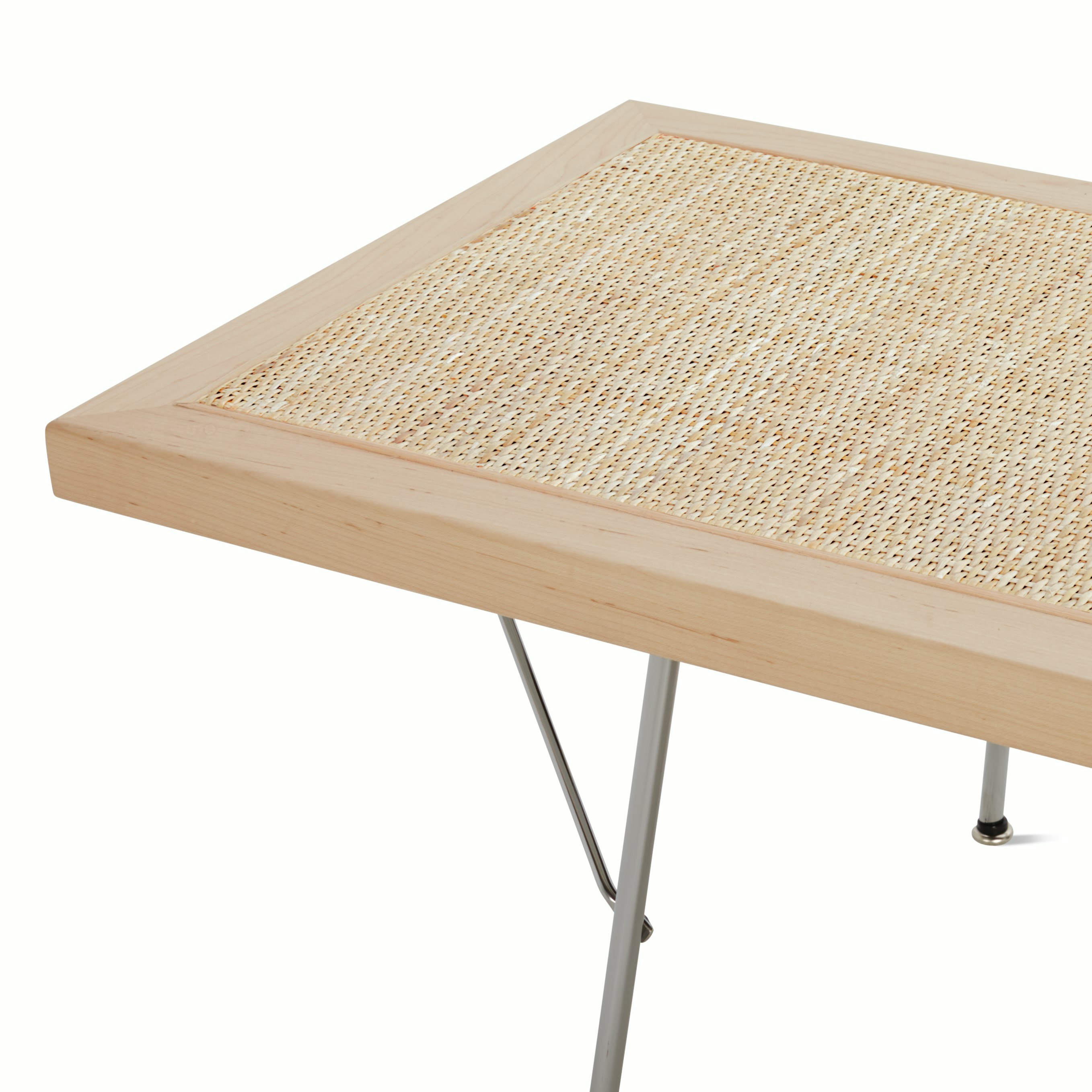 A close up detail of the maple frame, cane detailing, and metal legs of the Nelson Cane Bench.