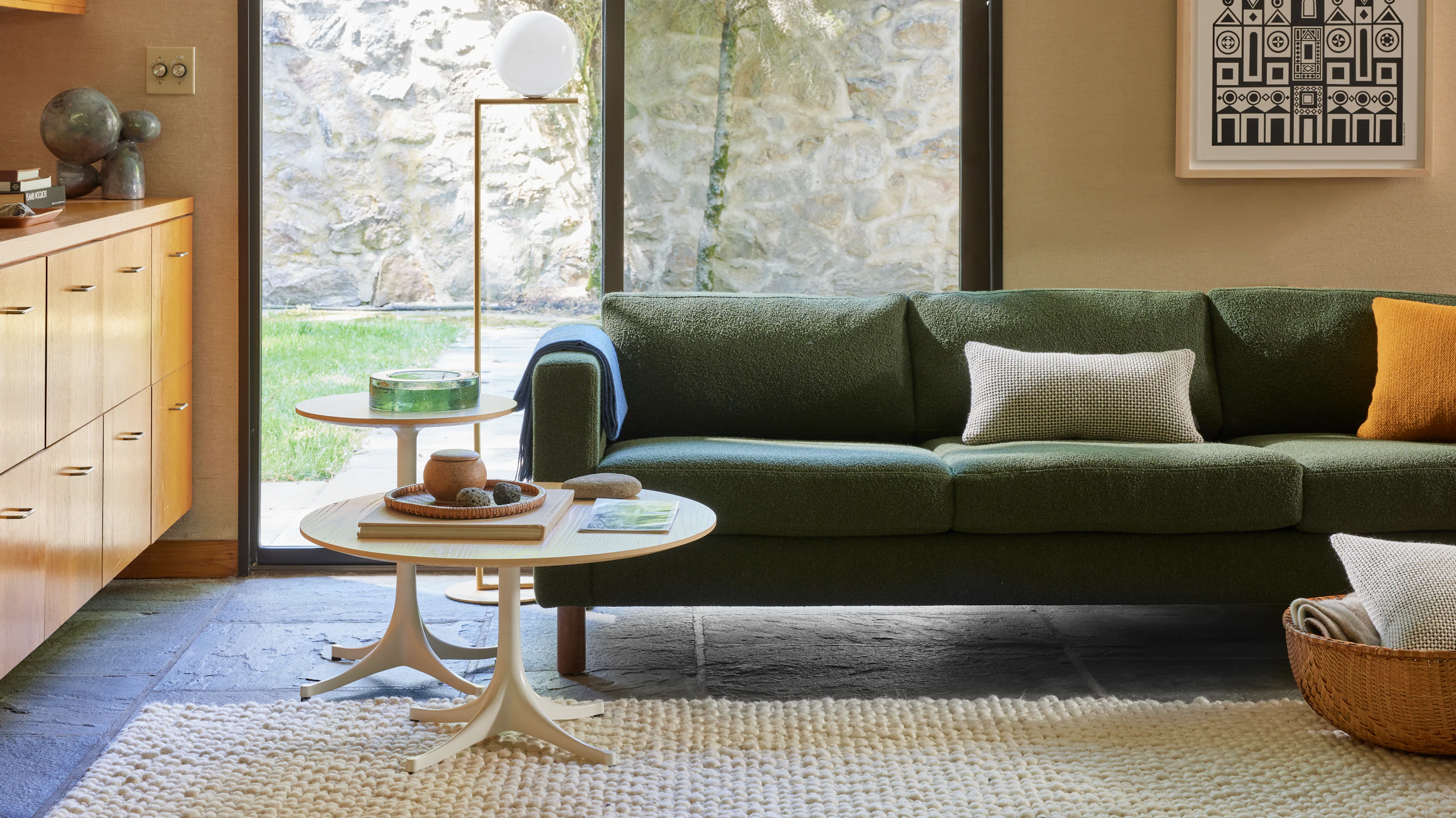 Environment of three seater Lispenard Sofa in dark green fabric and 6" walnut legs with and Nelson Tables.
