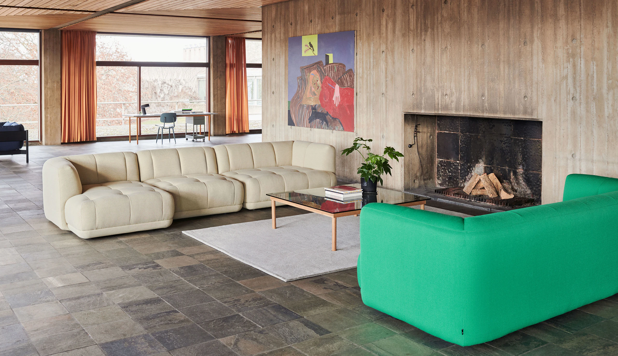 A square Kofi Coffee Table positioned next to a tan Quilton Sectional Sofa and an emerald Quilton Sofa.