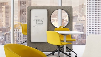 A brightly lit neighborhood workspace - designed to emphasize employee wellbeing - featuring a sit-to-stand table and Herman Miller Aeron chair overlooking a cityscape