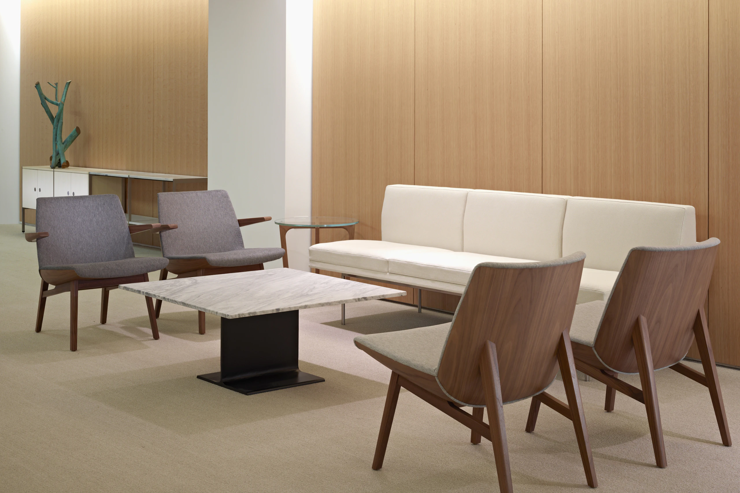 A sitting area featuring four gray Clamshell Lounge Chairs, an off-white Tuxedo Component sofa, and an I Beam occasional table.