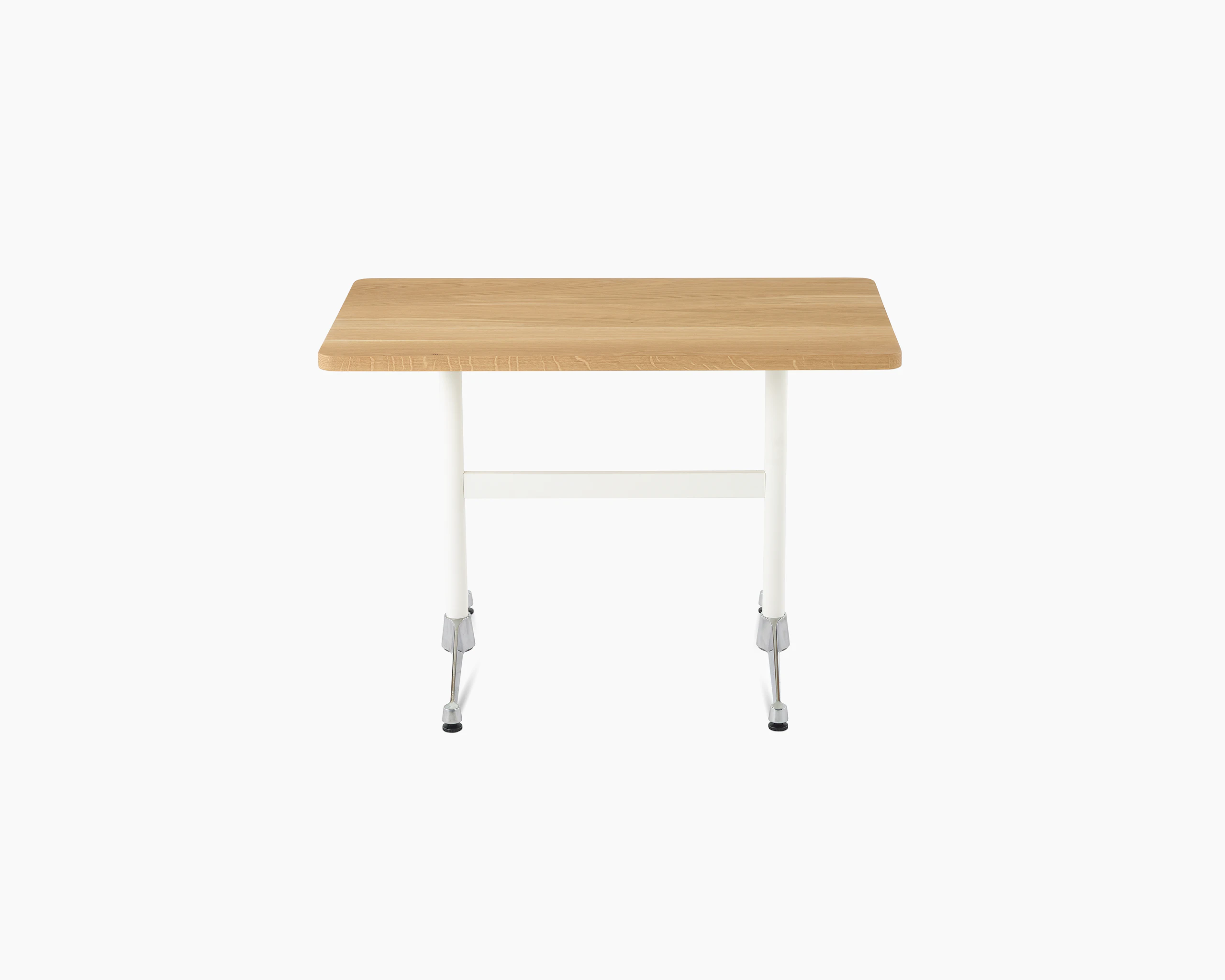 An Eames T-Leg Table configured as a desk, with an oak top, white legs, and chrome feet.