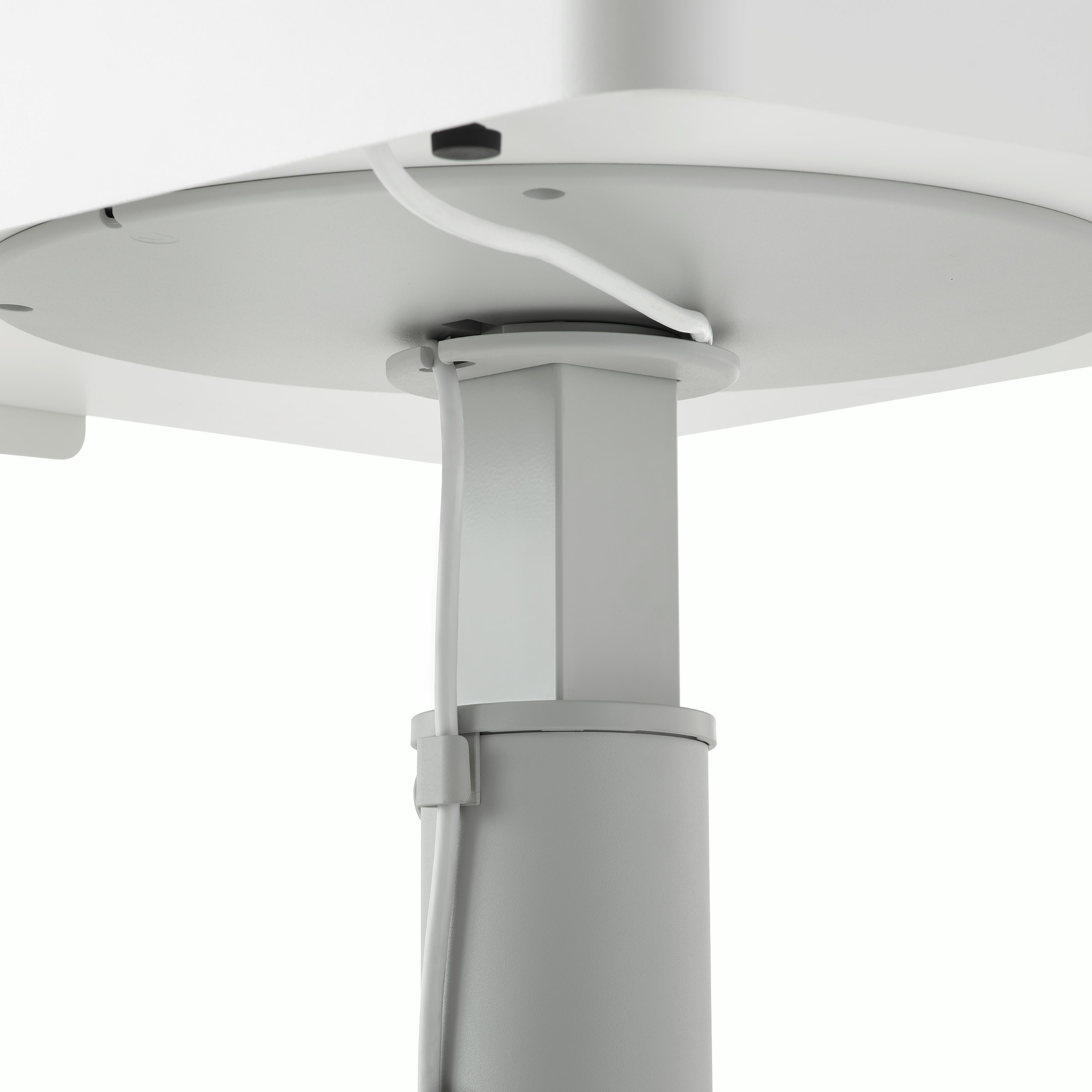 Detail image of a grey OE1 Sit-to-Stand Table with cable running from surface through the cable management clip.