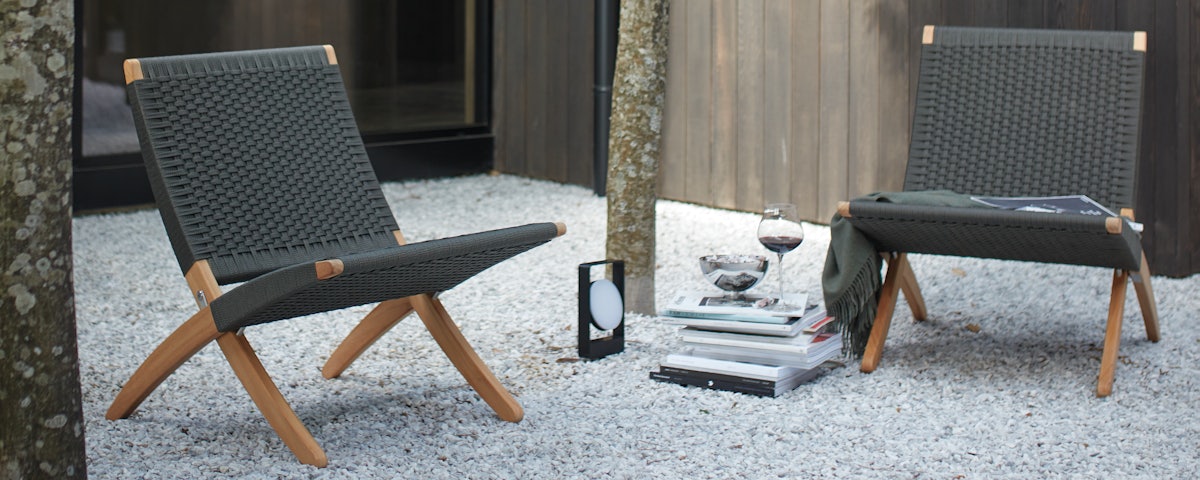 Two Cuba Outdoor Lounge Chairs in a stone pebble courtyard