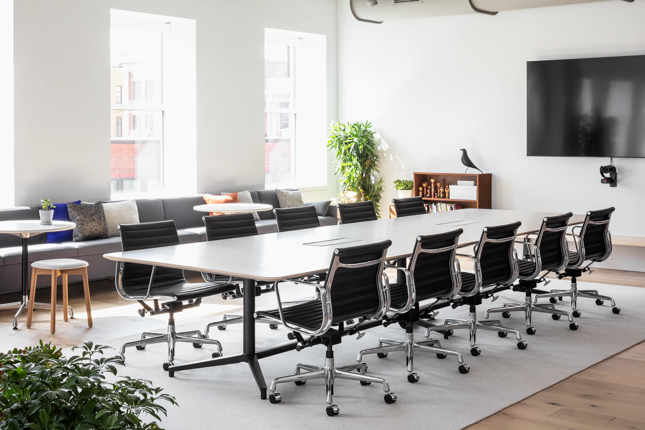A large well-lit conference room with a Headway Table and ten black Eames Aluminum Group chairs.