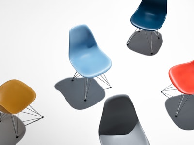 A collection of Eames Moulded Plastic Chairs in a variety of different colours.