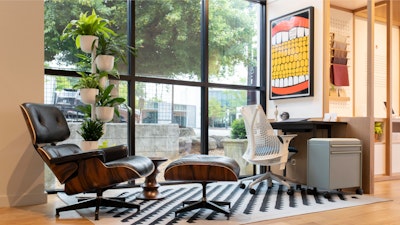 Several Herman Miller products, including an Eames Lounge Chair and Ottoman, Sayl Chair, and OE1 Storage Trolley, on a black and white rug at the Herman Miller Atlanta store
