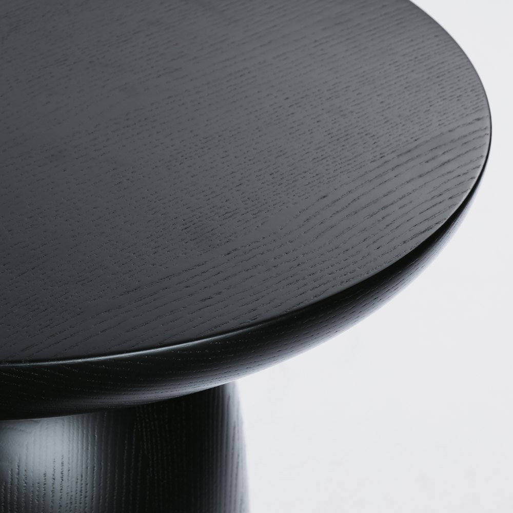 A close up view of the top surface of a Hew Side Table in a painted black finish.