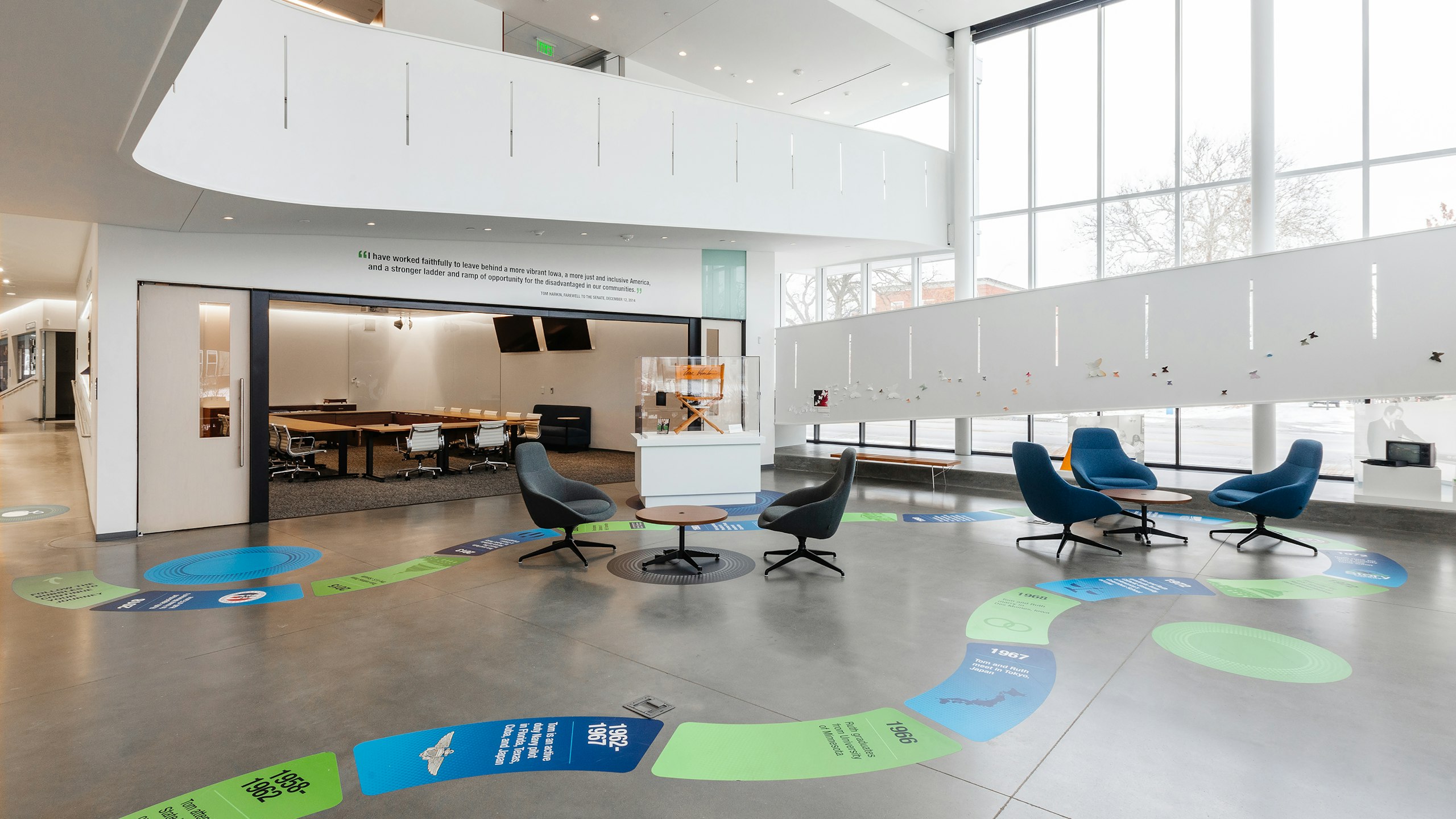 Large open area with lounge seating and occasional tables outside a large meeting space.