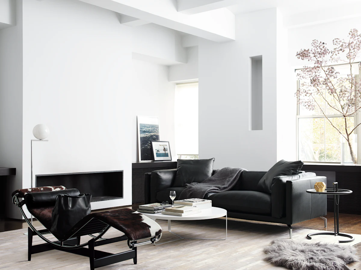 Bright white living room with black sofas and glass coffee table