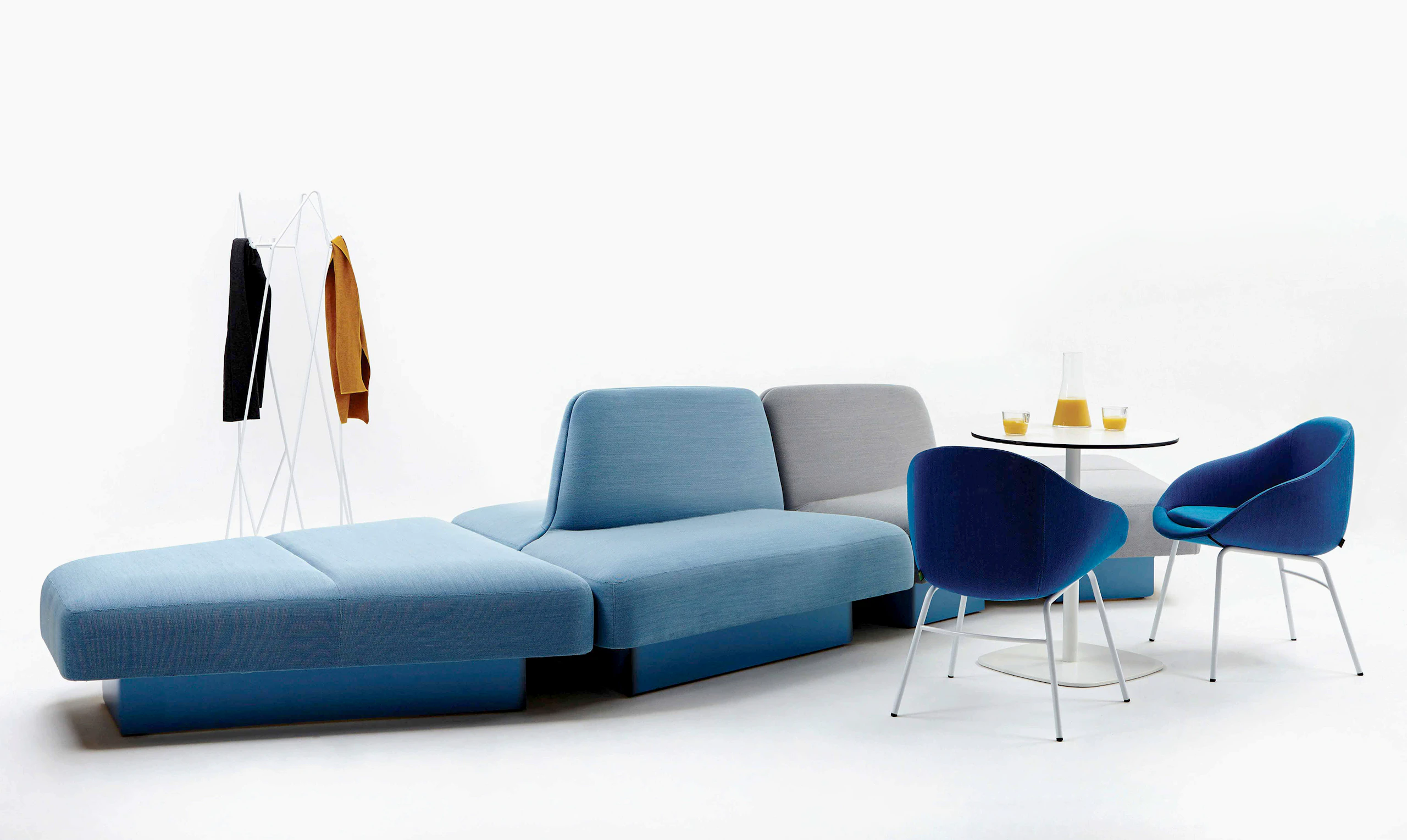 White sweep view of large modular sofa with chairs, table and coat stand.