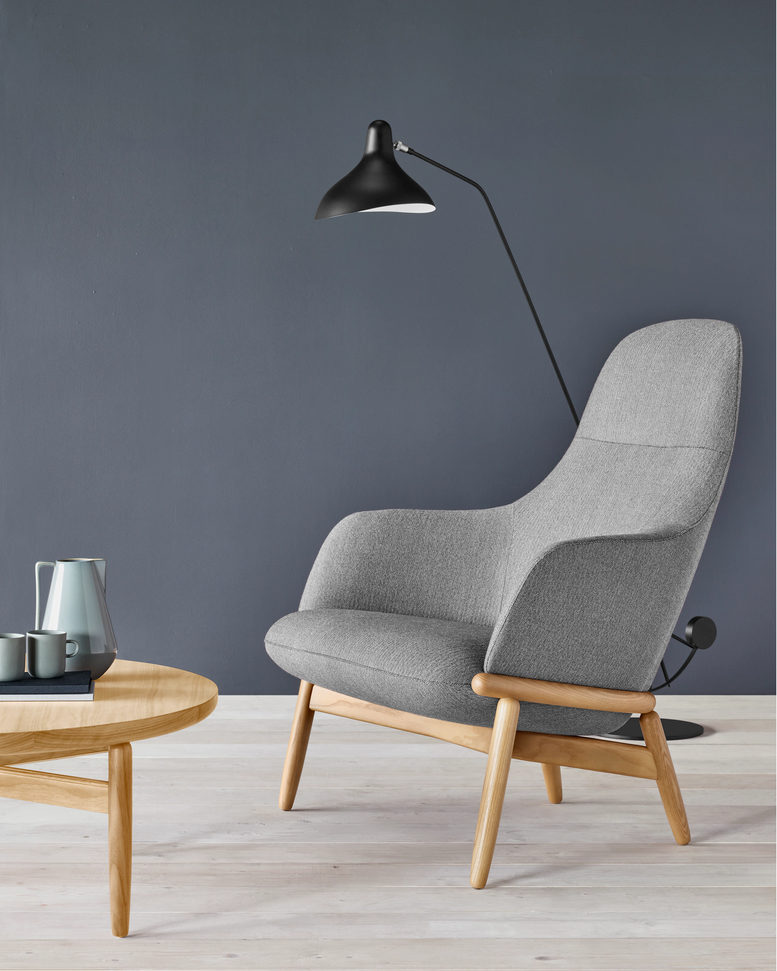 A high-back Reframe Lounge Chair in Panno di Dolce Flannel next to a Reframe Table with a black lamp in the background.