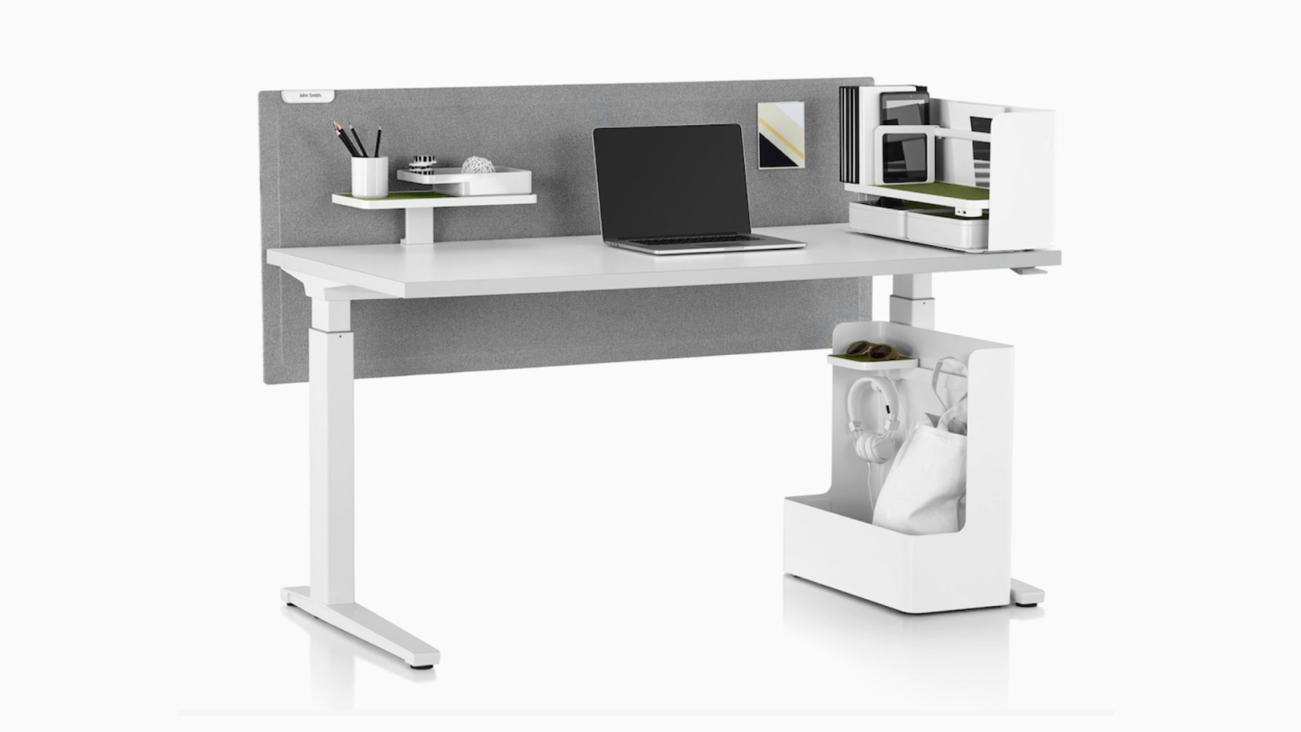 A laptop, miscellaneous office supplies, and Ubi Work Tools sitting atop a Renew Sit-to-Stand table