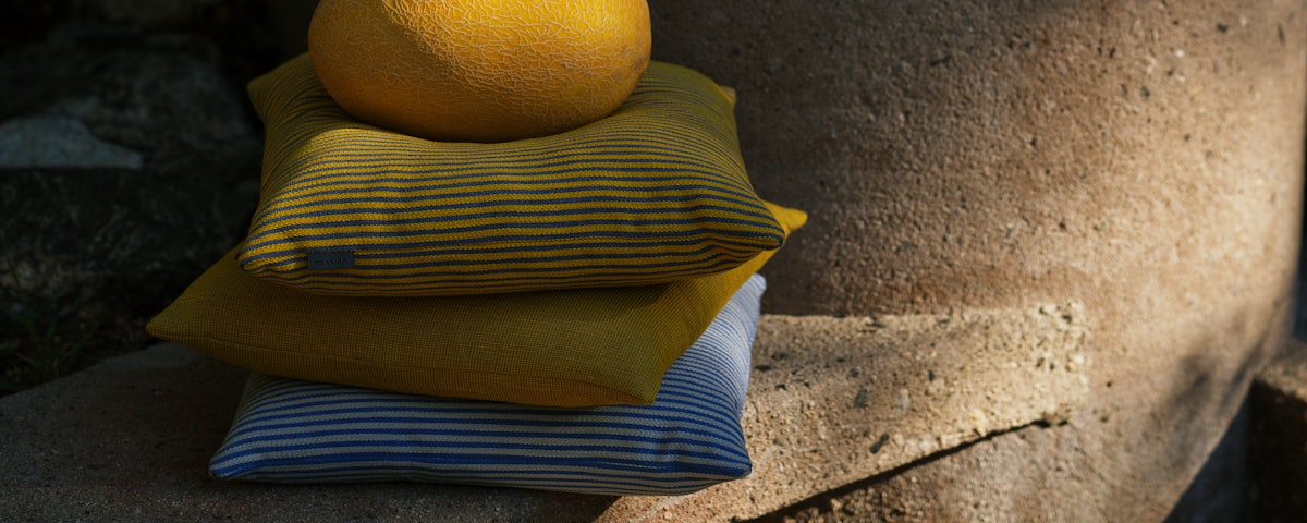Concord Stripe and Ribbed Weave Outdoor Pillow with a melon resting on top