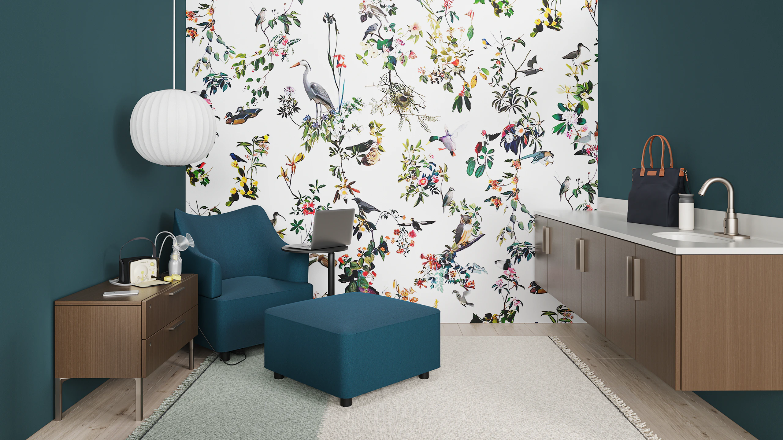 Dark blue-green fully upholstered Plex Club Chair and ottoman with black feet shown in a private Mother's Room. Setting includes a Plex adjustable height work table with ebony top and black base, credenza in light brown walnut with metallic brown legs, light brown walnut cabinetry with sink, faucet and pearl gray Corian top and Nelson Ball Bubble pendant. The Plex Club chair has an optional power unit and housing.