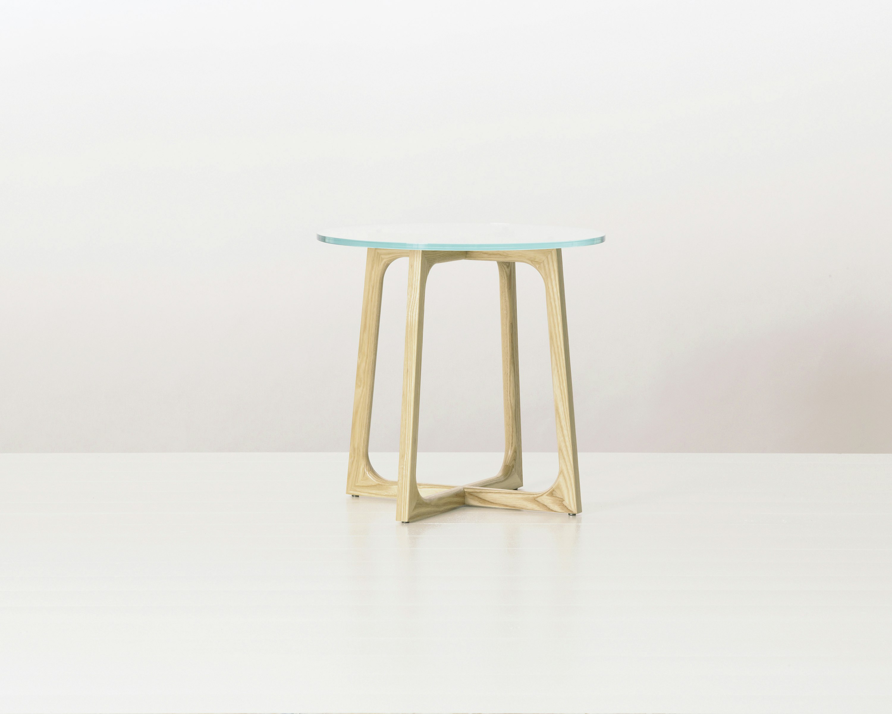 A round Loophole side table with a glass top and an light-ash base.