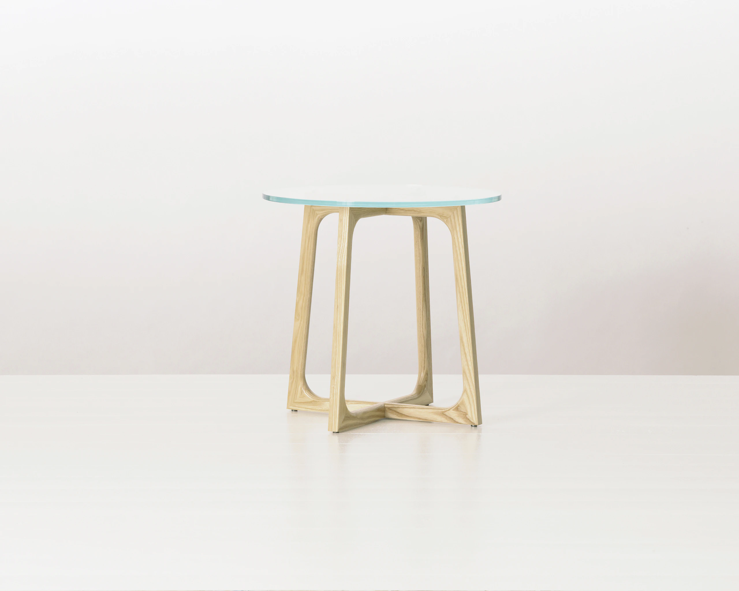 A round Loophole side table with a glass top and an light-ash base.