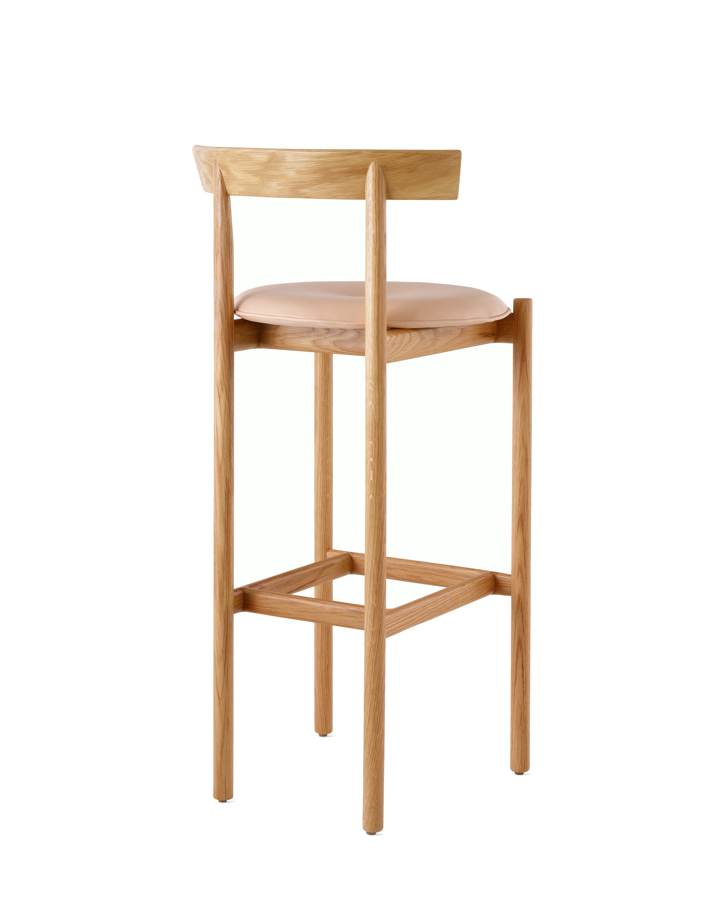 An oak bar-height Comma Stool with a seat pad, viewed from the back at an angle.