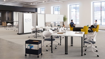 Two people sitting in a brightly lit, open floorplan community setting featuring Herman Miller Fuld Nesting chairs, yellow NaughtOne Pippin chairs, and Herman Miller OE1 Agile Walls and Storage Trolleys.
