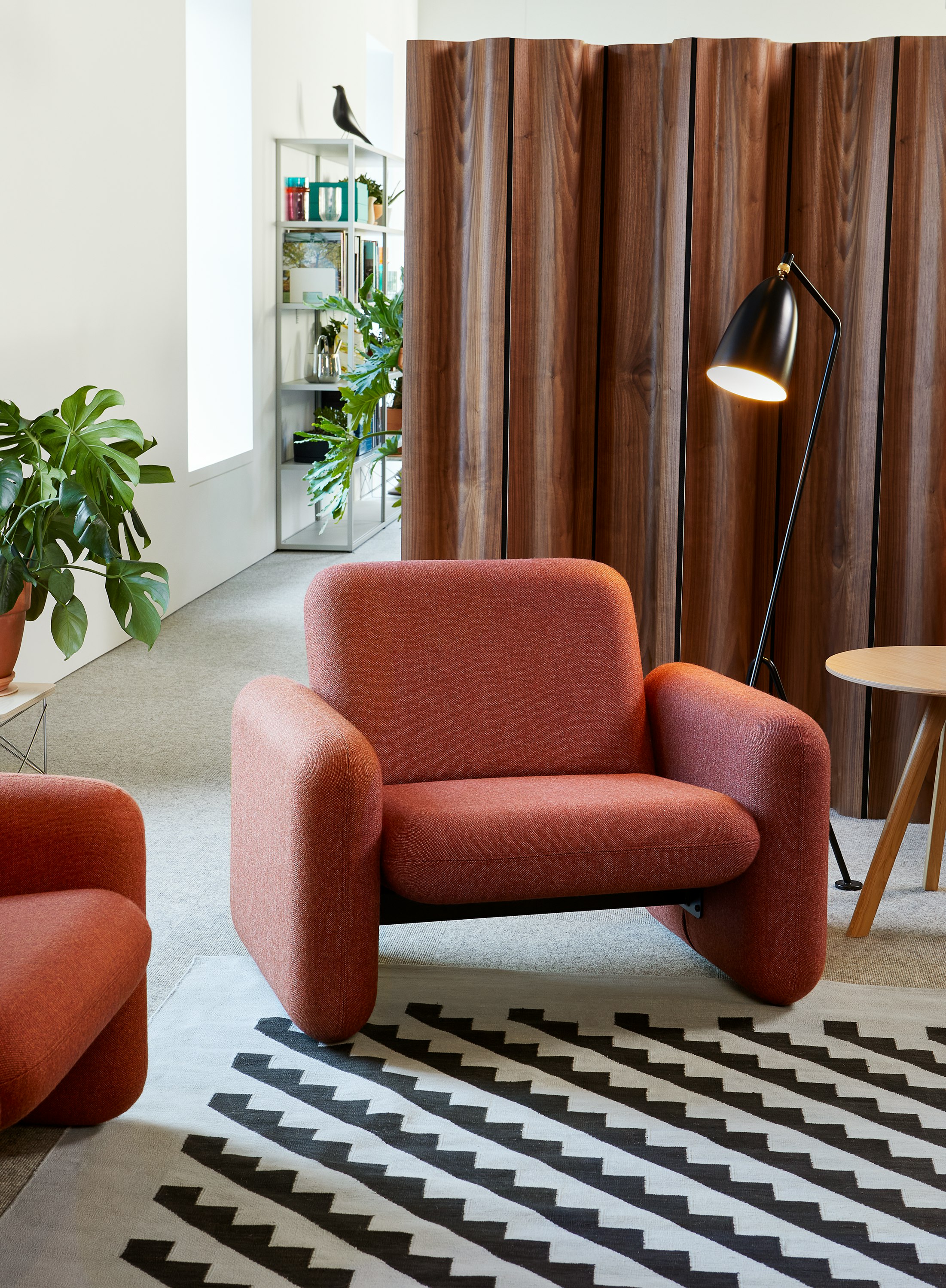 A Wilkes Modular Sofa Group chair in orange-brown next to a black Grasshopper lamp and in front of a brown Eames Folding Screen .