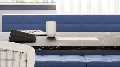 A coffee mug and assorted work papers atop a black and white Knoll Grasshopper table that features a blue Geiger Tuxedo Component Lounge and white Knoll Bertoia chair in a group conference room setting designed to facilitate employee connection.
