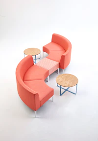 A coral patterned Symbol Single Stool joining two coral Symbol Modular Seating- 90 Degree curve pieces.