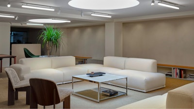 A white L-shaped sofa and two chairs arranged around a square coffee table at the MillerKnoll London Flagship store
