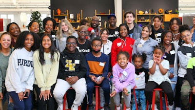 Eine Gruppe von MillerKnoll-Mitarbeitern mit Kindern von der I AM Akademie in einer Büroumgebung.