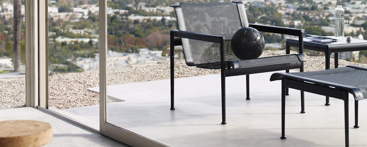 1966 Collection Ottoman and 1966 Collection Lounge Chair with a black soccer ball in a patio setting