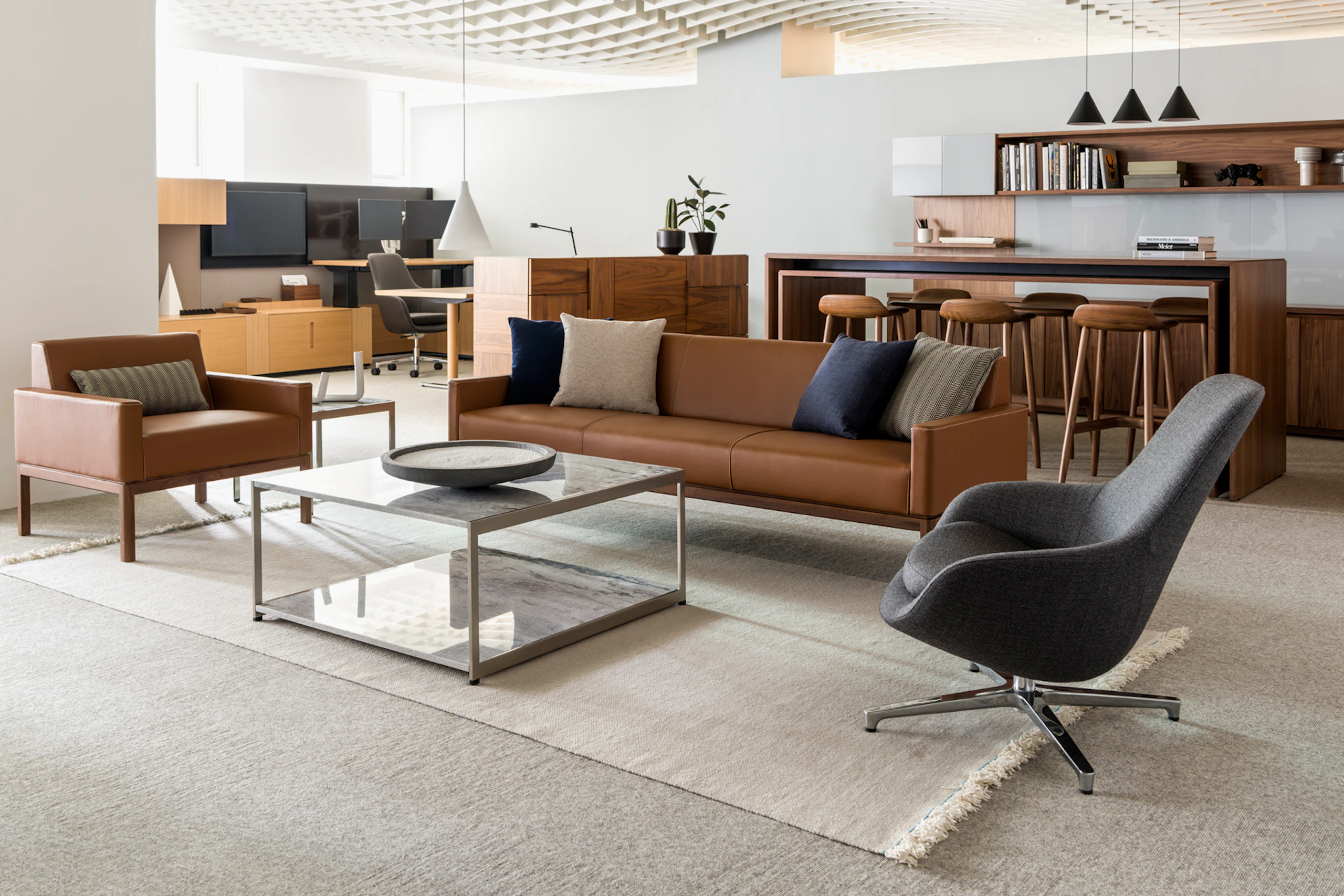 An open office space featuring a sitting area that includes Wood Base Lounge Seating and an H Frame coffee table with stone upper and lower surfaces.