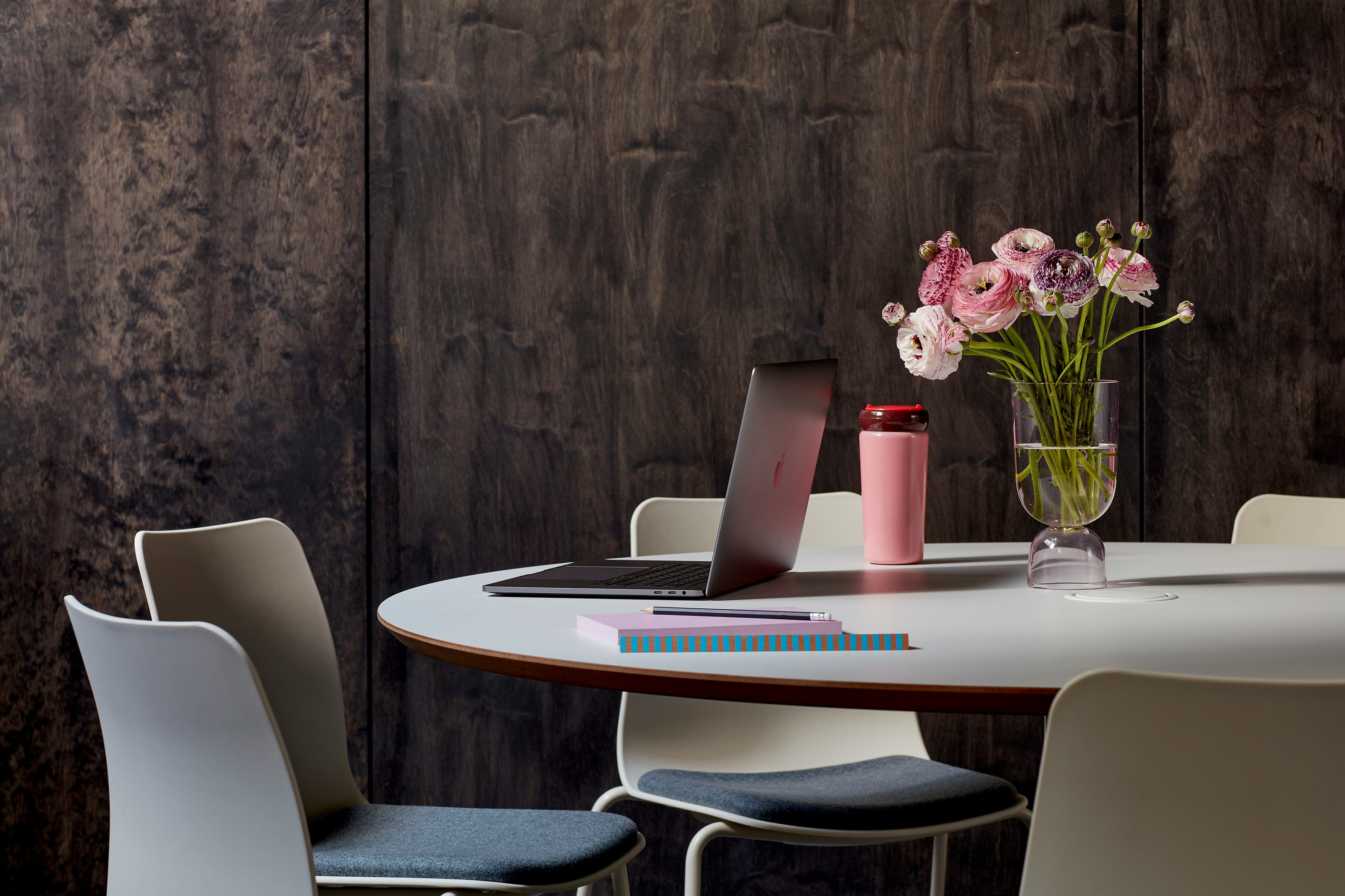 Cluster of Polly chairs sitting around a circular Megaped table, set against a wooden wall.