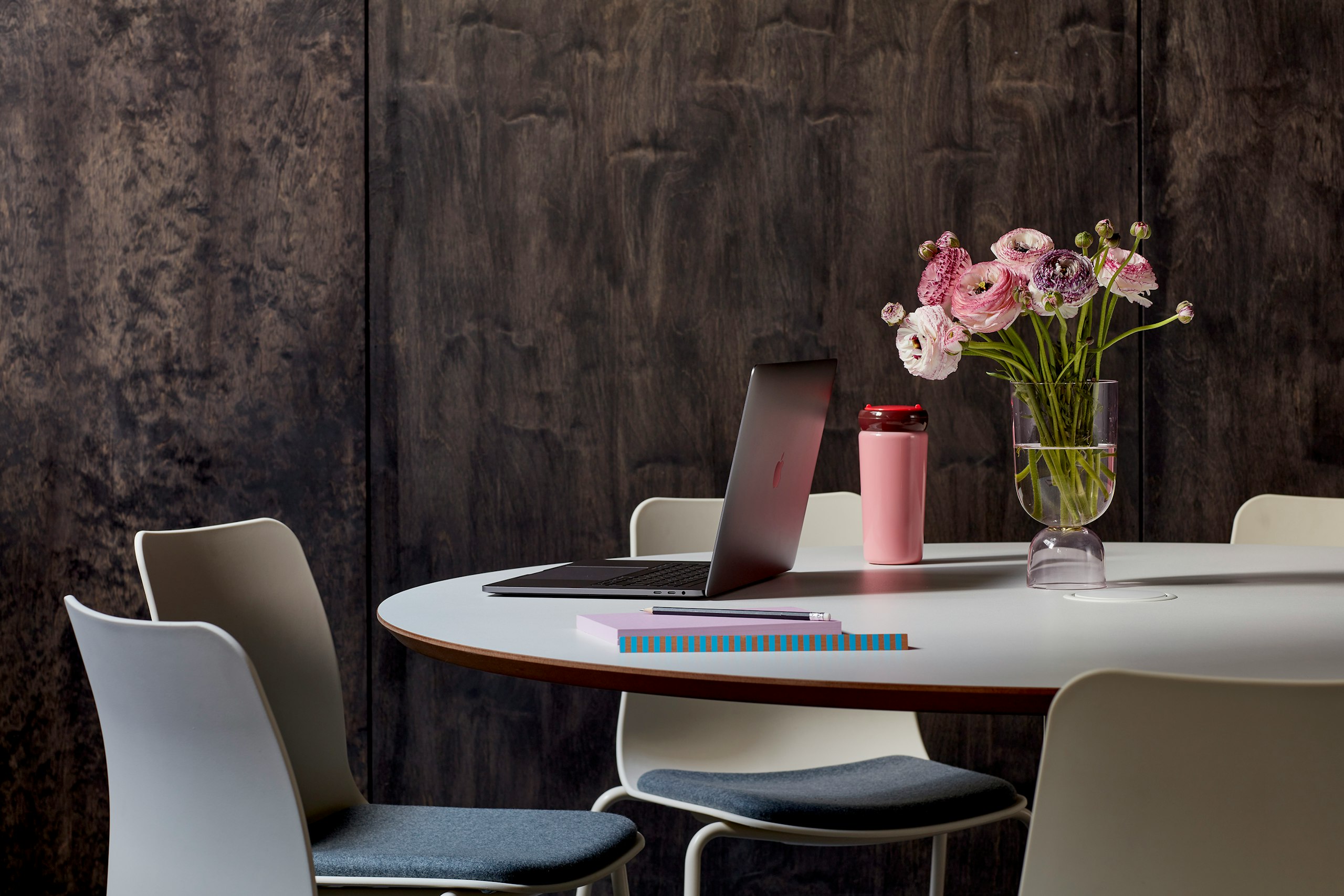 Cluster of Polly chairs sitting around a circular Megaped table, set against a wooden wall.