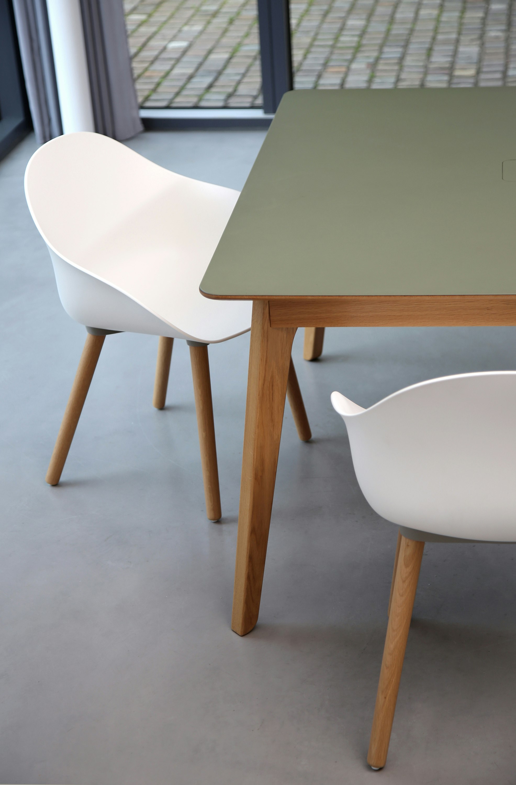 Two white Ruby Side Chairs on oak dowel bases with a table.
