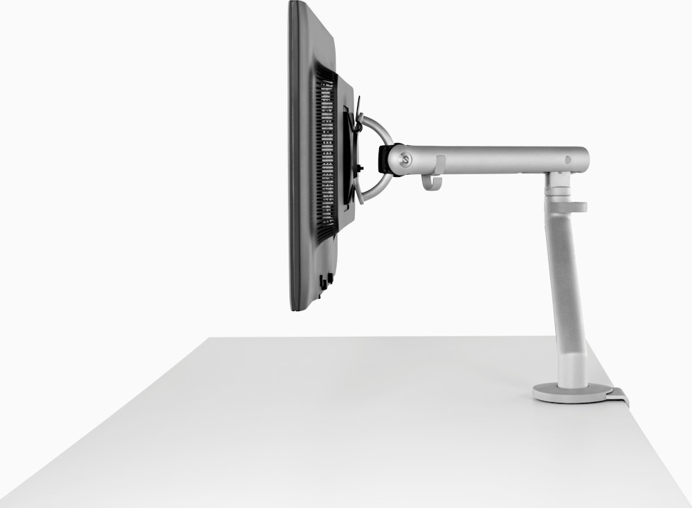 A computer monitor supported by a silver Flo Monitor Arm.