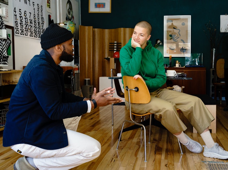 Jared Blake talking with a friend about the Eames Molded Plywood Dining Chair.