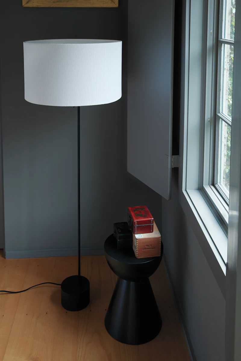 Close-up of a black wooden stool with a white lampshade on top