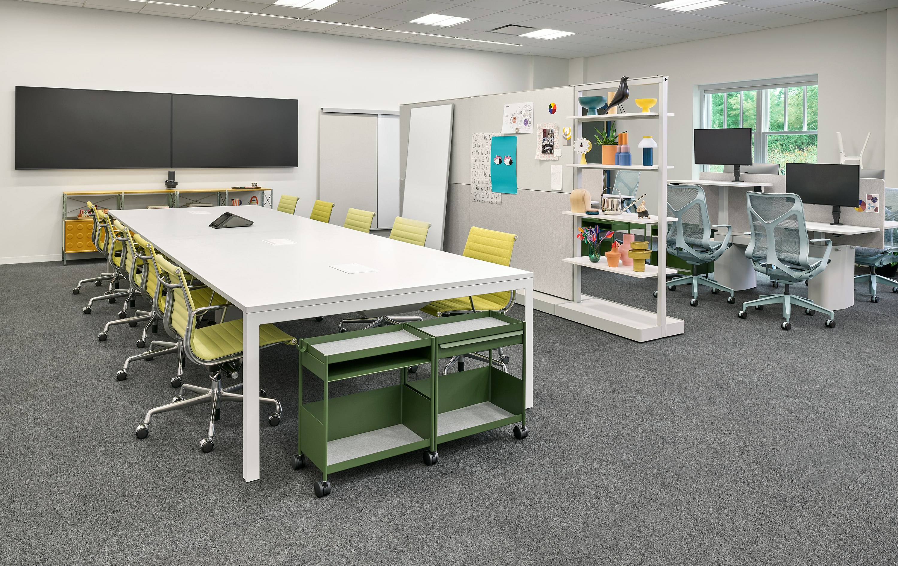 A collaborative office space with a large white Layout Studio Project Table surrounded by Lemon yellow Eames Aluminum Group Management Chairs.