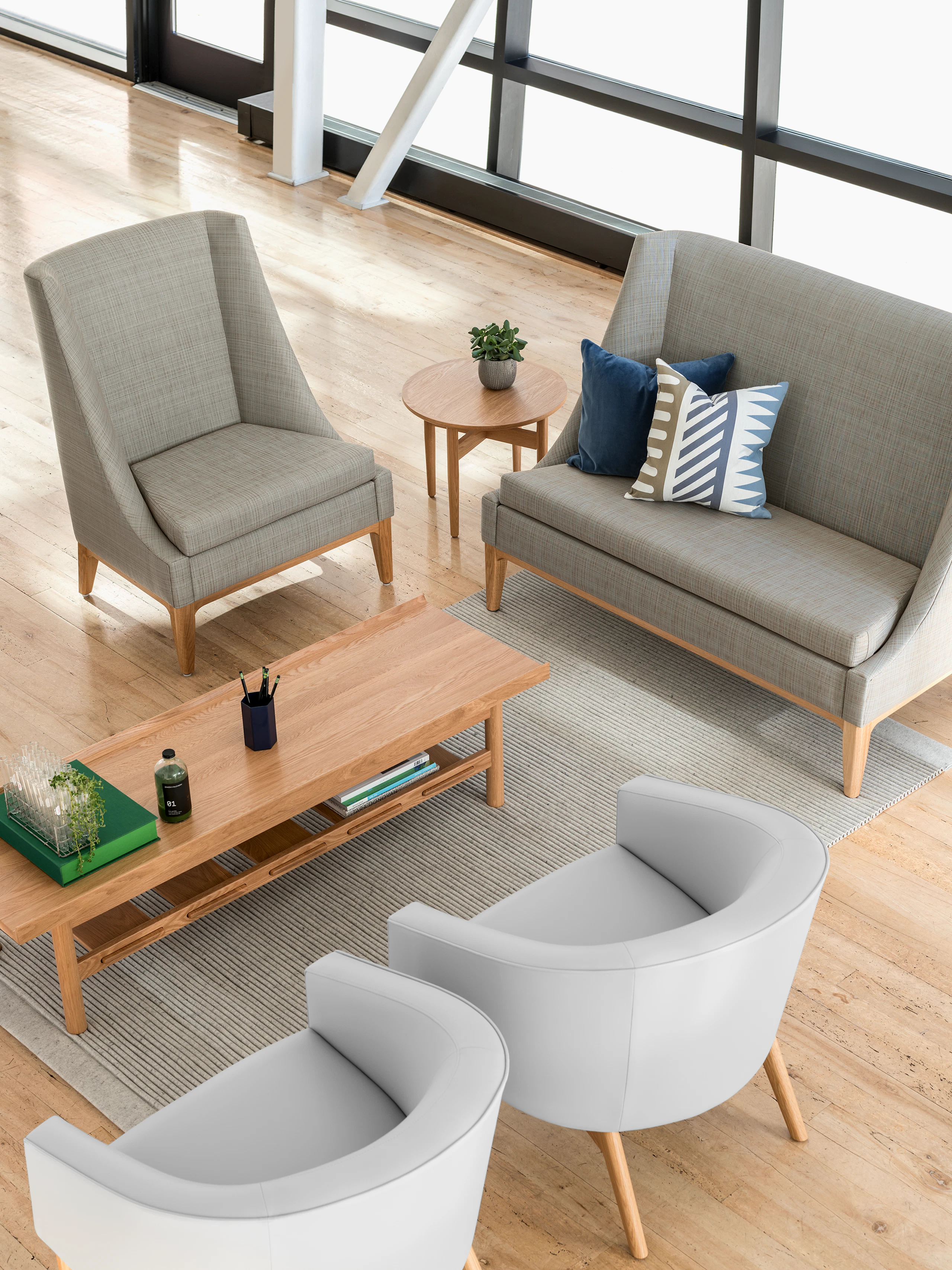 A window filled waiting area featuring a Nemschoff Iris Settee, Nemschoff Sophora Lounge Chairs, and a Nemschoff Tamarack Table and Bench.
