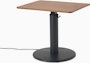 OE1 Sit-to-Stand Table with black base and brown rectangular surface viewed from a front angle. 