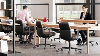 Several black Herman Miller Asari Chairs placed around a Muuto Linear System and Mounted Lamps allowing team members to connect while working individually.